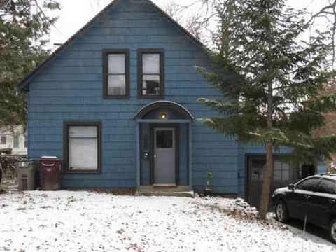 A blue house with a black car parked in front.