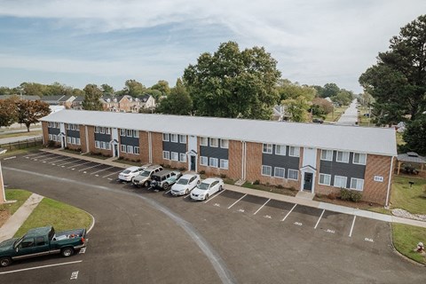 an apartment building with cars parked in a parking lot