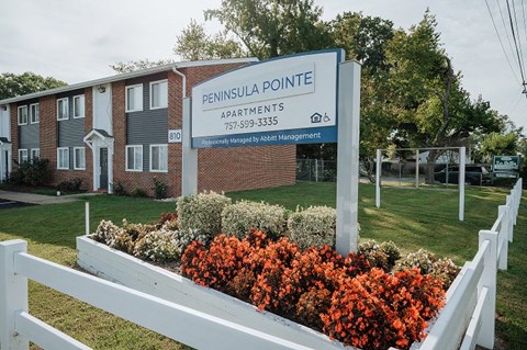 a building with a sign in front of a bed of flowers