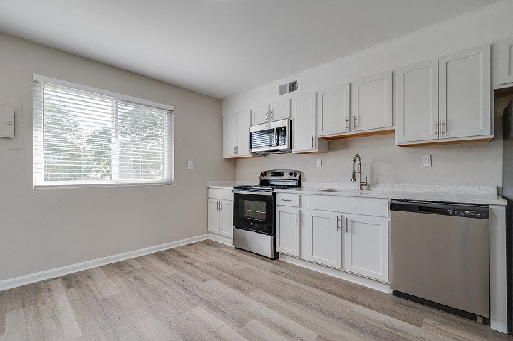 an empty kitchen with white cabinets and a window