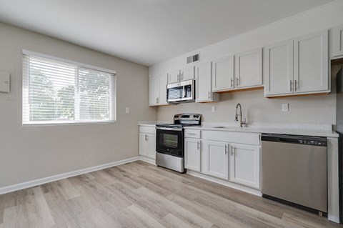 an empty kitchen with white cabinets and a window
