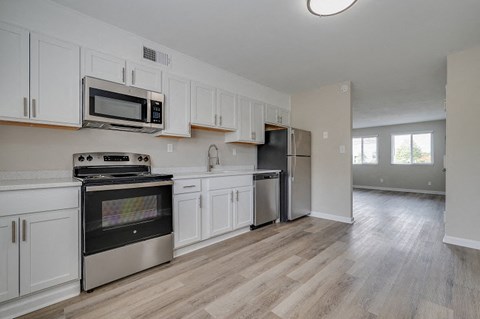 an empty kitchen with stainless steel appliances and white cabinets