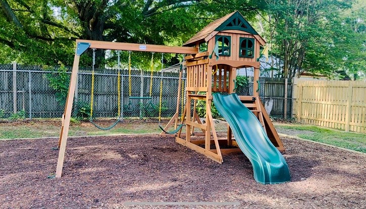 a wooden swing set with a slide in a backyard
