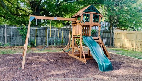 a wooden swing set with a slide in a backyard
