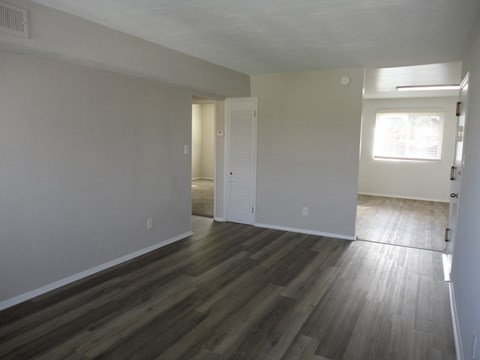 an empty living room with wooden floors and white walls