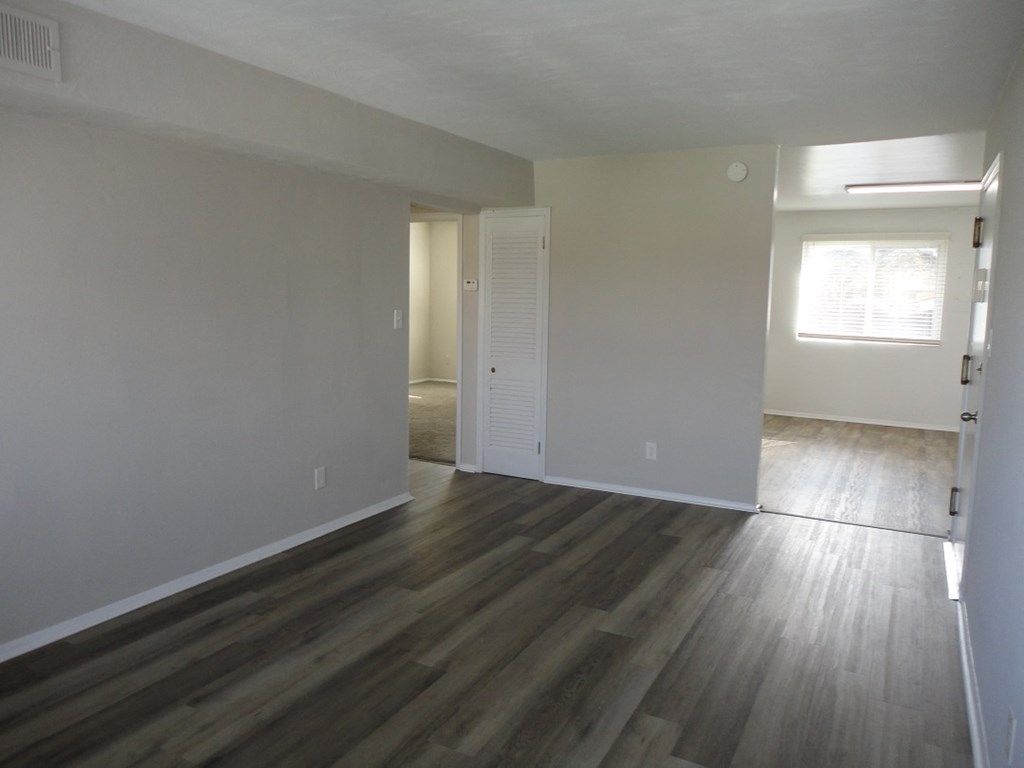 an empty living room with wooden floors and white walls