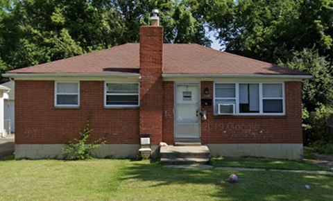 a red brick house with a lawn and trees