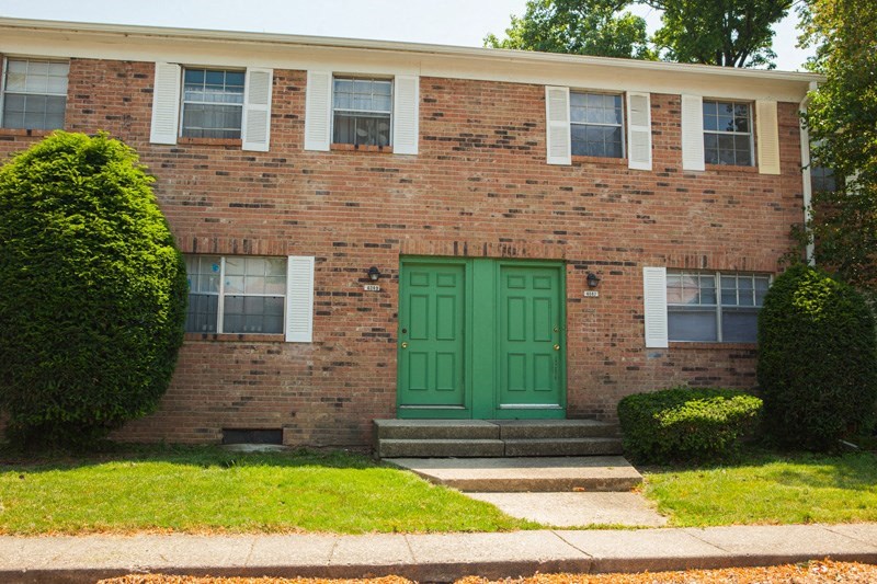 the front of a brick house with green doors