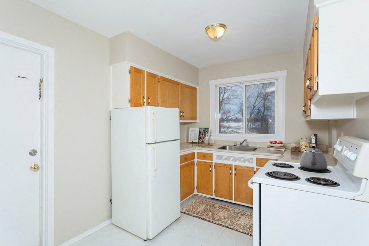 A kitchen with white appliances and wooden cabinets.