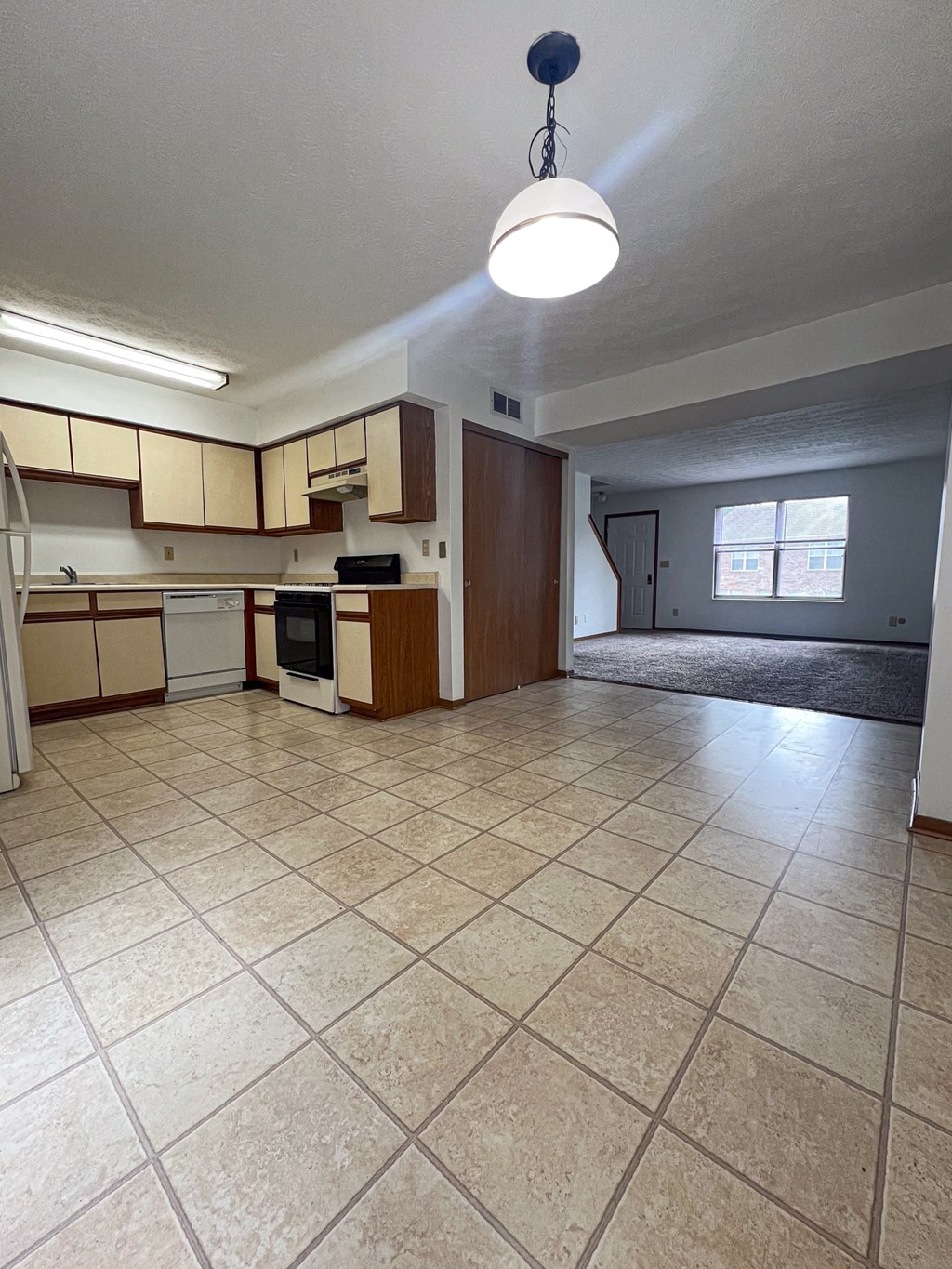an empty kitchen and living room with tile flooring