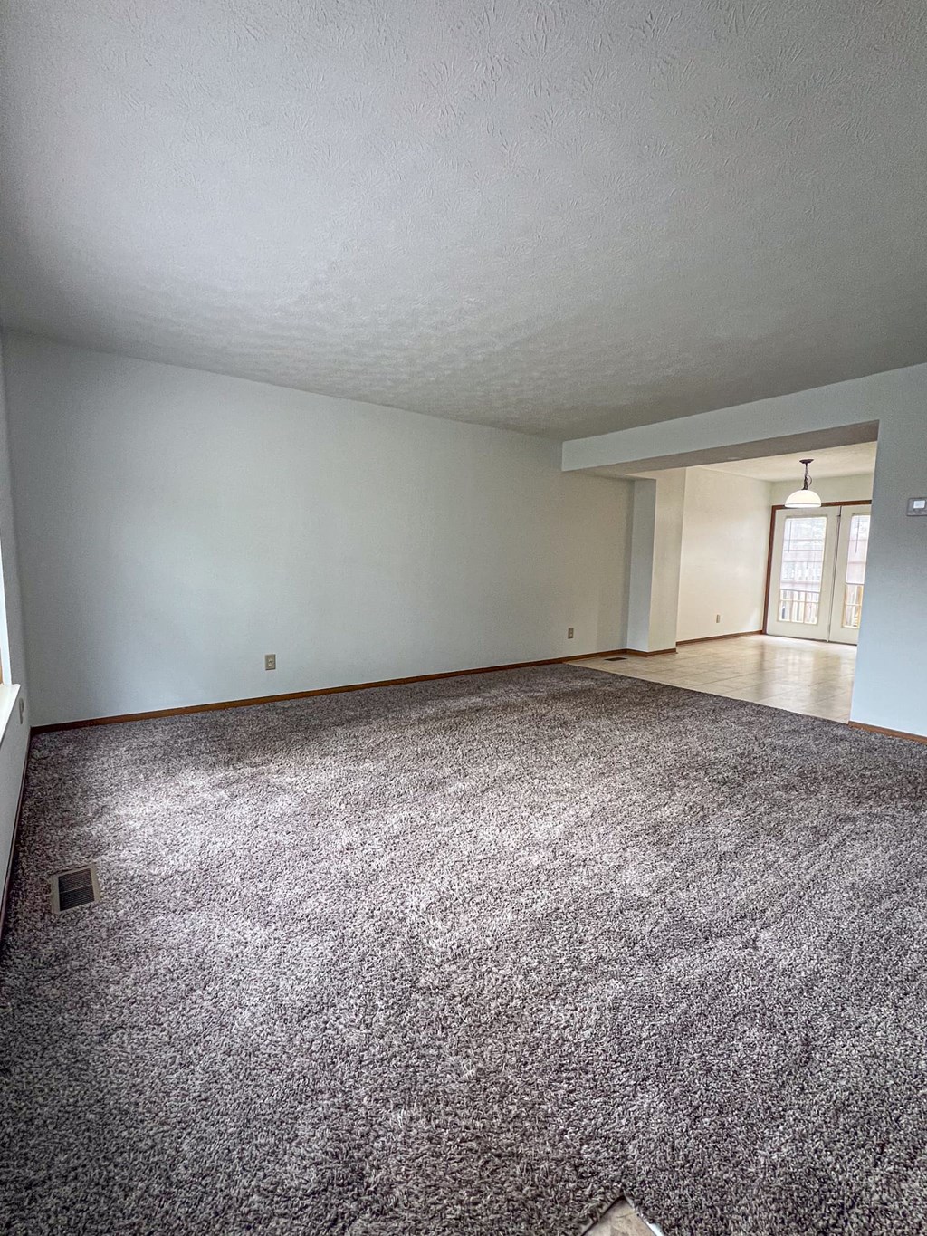 an empty living room with carpet and white walls