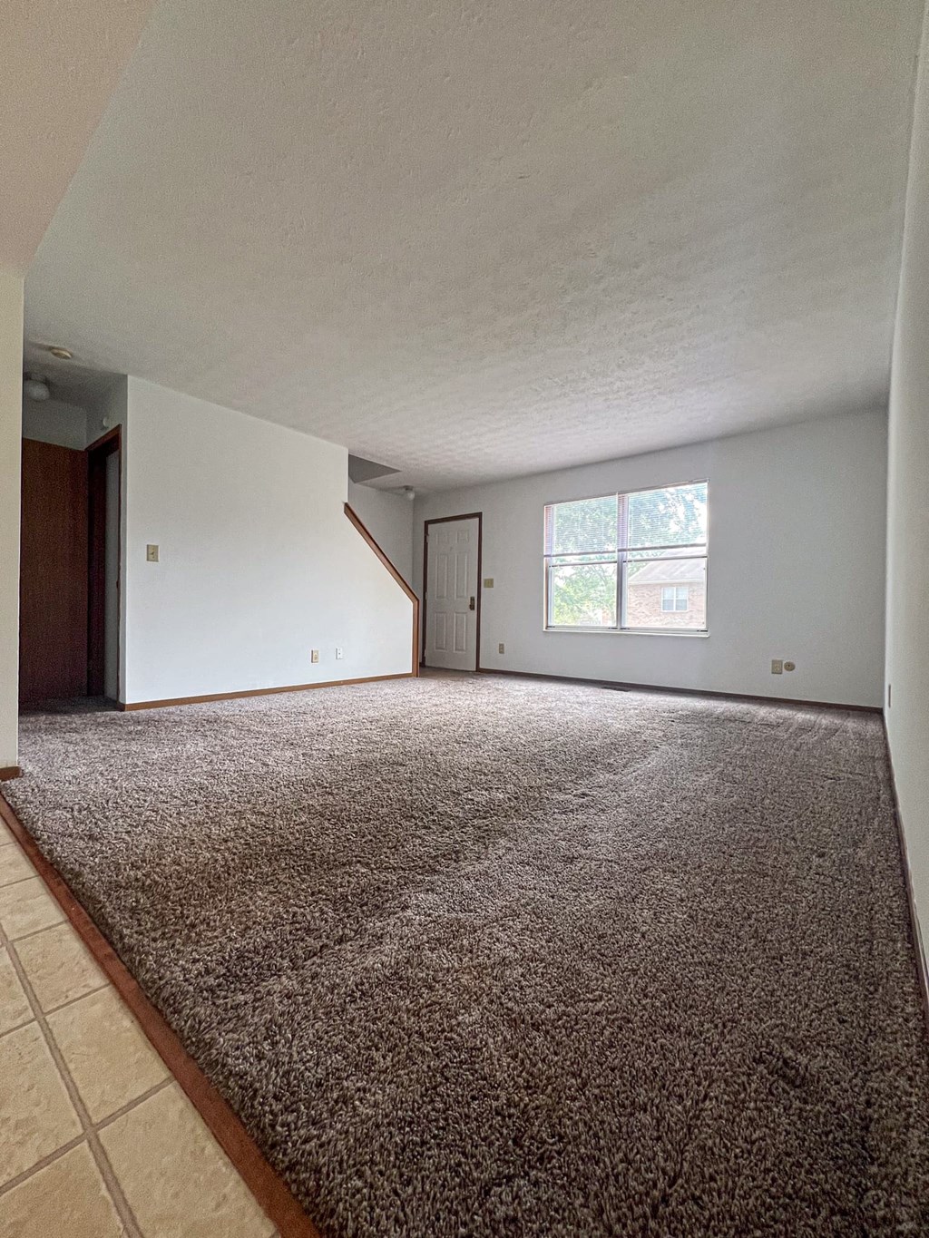 an empty living room with carpet and a window