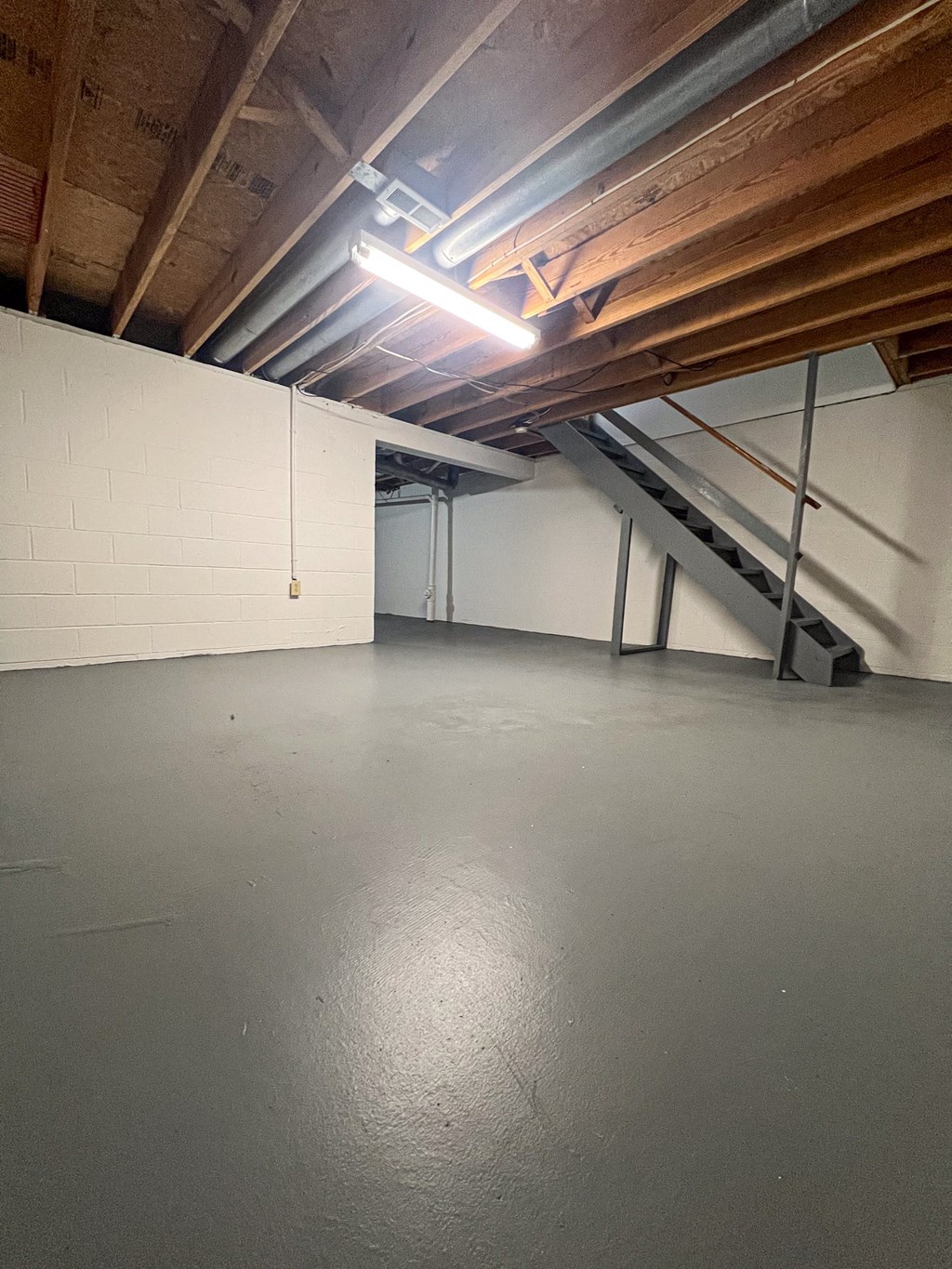the interior of a garage with a concrete floor and exposed wooden beams