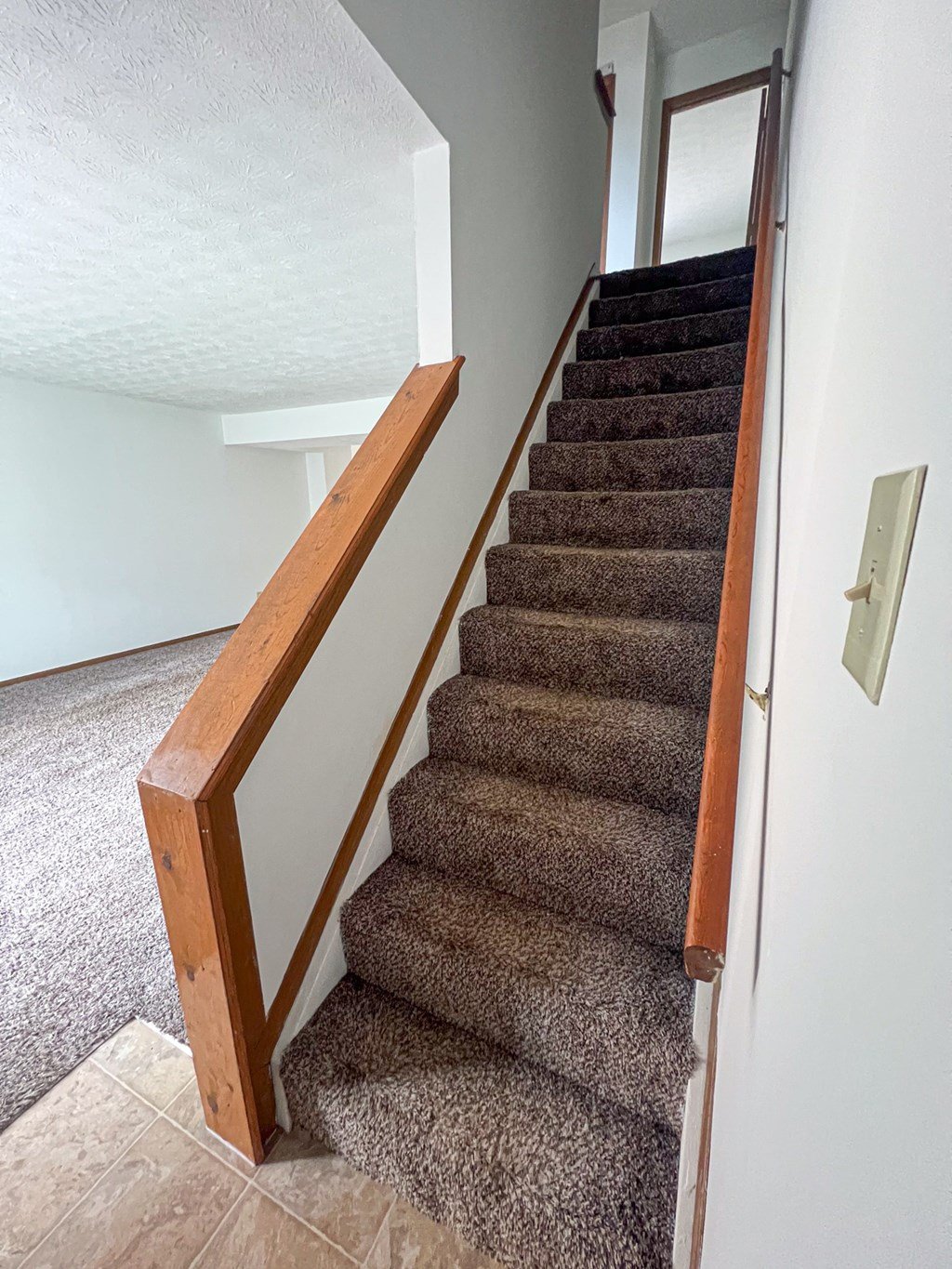 a staircase with a wooden railing and carpeted stairs