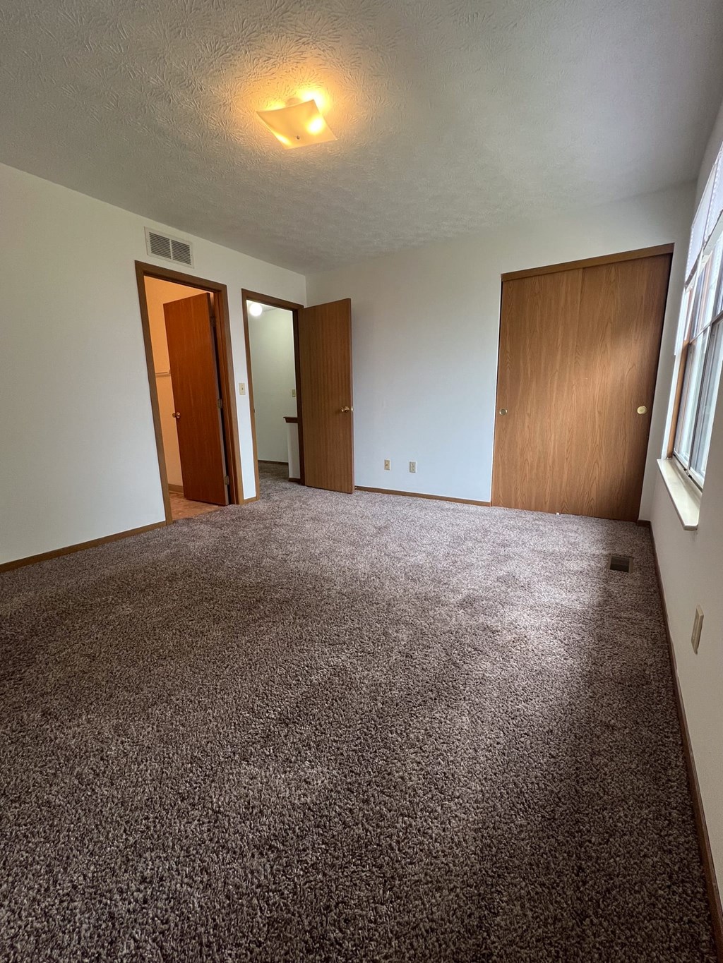 an empty living room with a carpeted floor and a window
