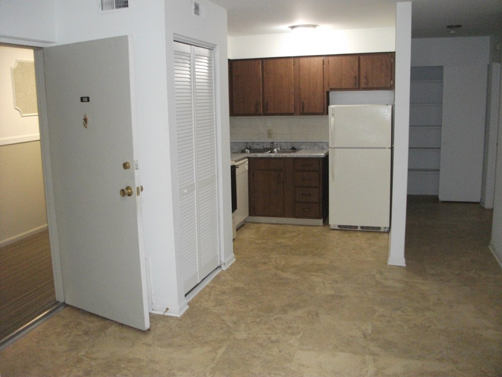 an empty kitchen with white appliances and wooden cabinets