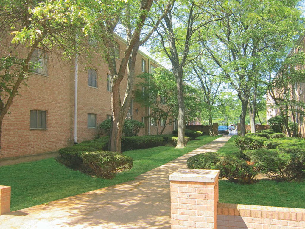a walkway in front of a brick apartment building
