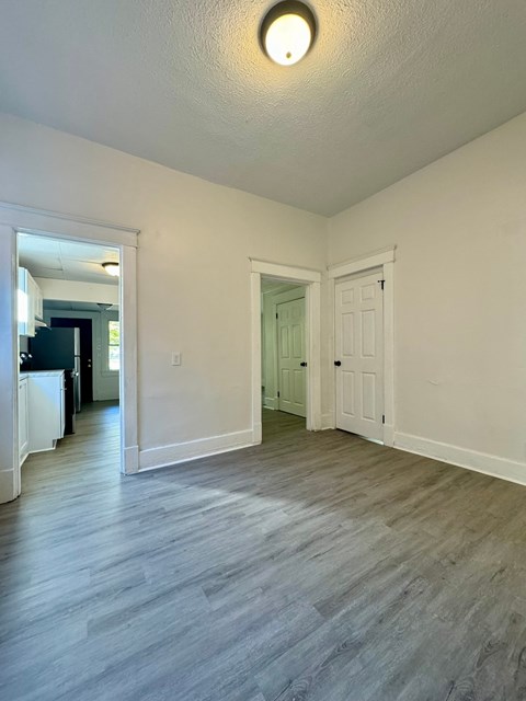an empty living room and hallway with white walls and wood floors