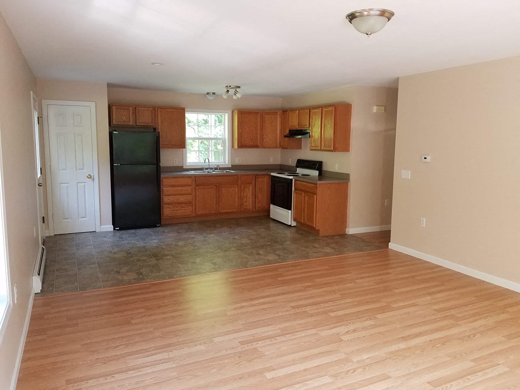 A kitchen with wooden cabinets and a black refrigerator.