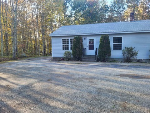 A white house with a gravel driveway in front.