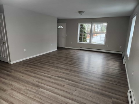 A room with wooden flooring and a window with a view of a tree.