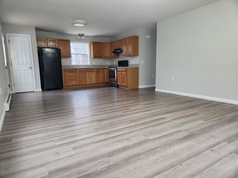 A kitchen with wooden cabinets and a black refrigerator.