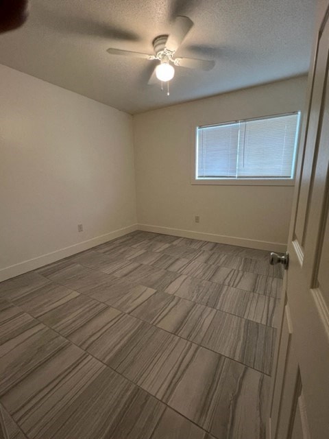a empty room with a ceiling fan and a window