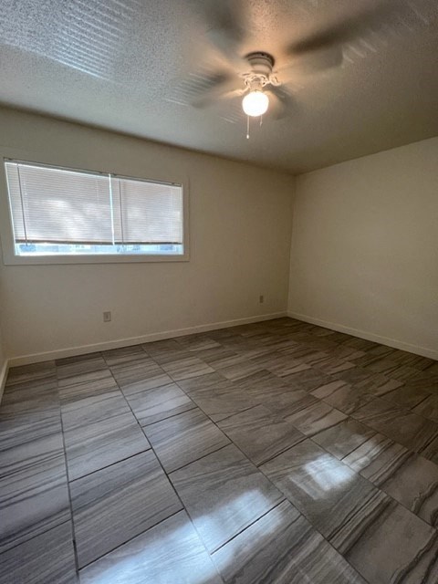 an empty room with a ceiling fan and a window