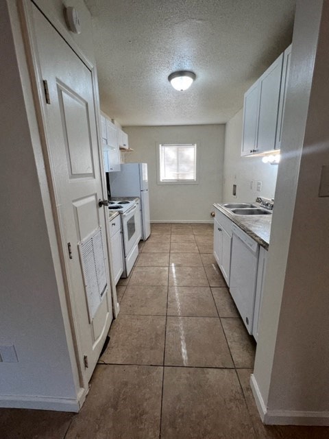 an empty kitchen with white cabinets and white appliances