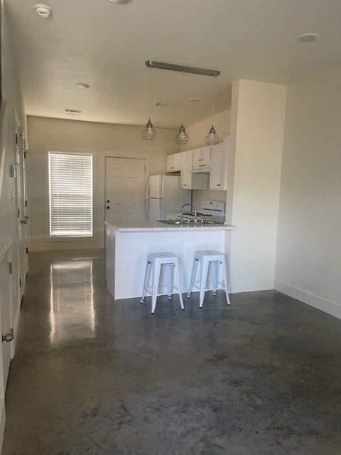 an empty kitchen with stools and a white counter top
