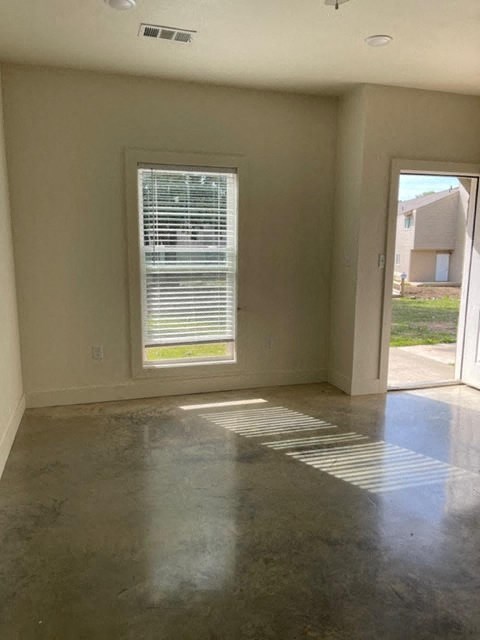 an empty living room with a window and concrete floor