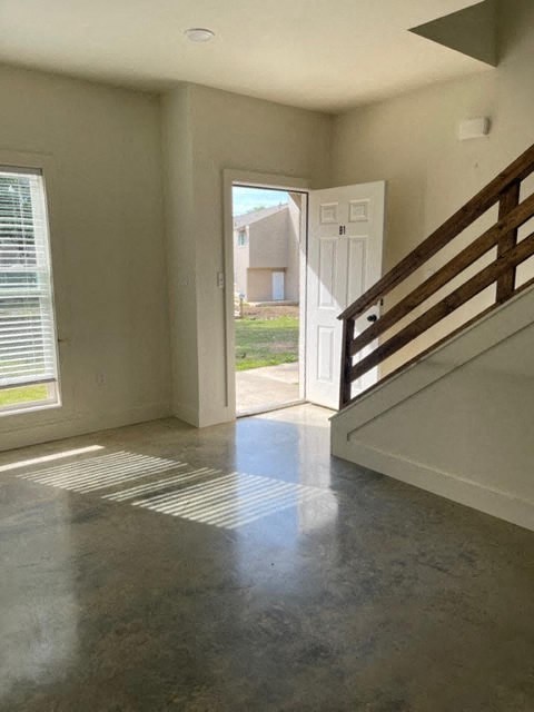 an empty living room with a staircase and a door