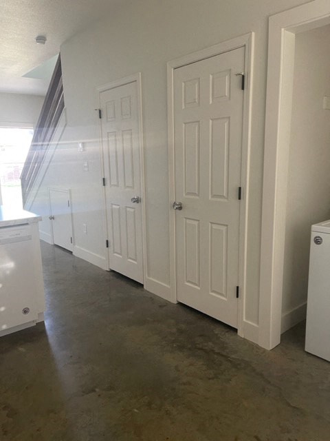 a hallway with white doors and a concrete floor