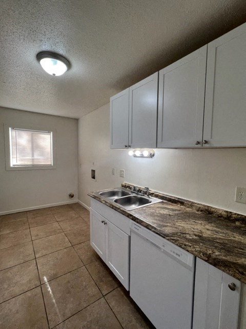 an empty kitchen with white cabinets and a sink