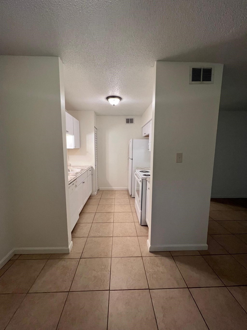 a view of a kitchen with a tile floor and white appliances