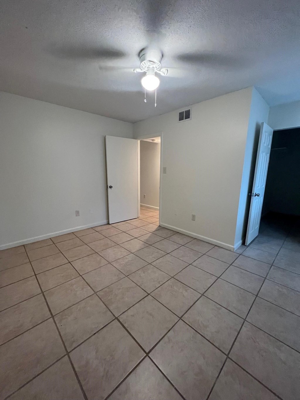 an empty living room with tile floors and a ceiling fan