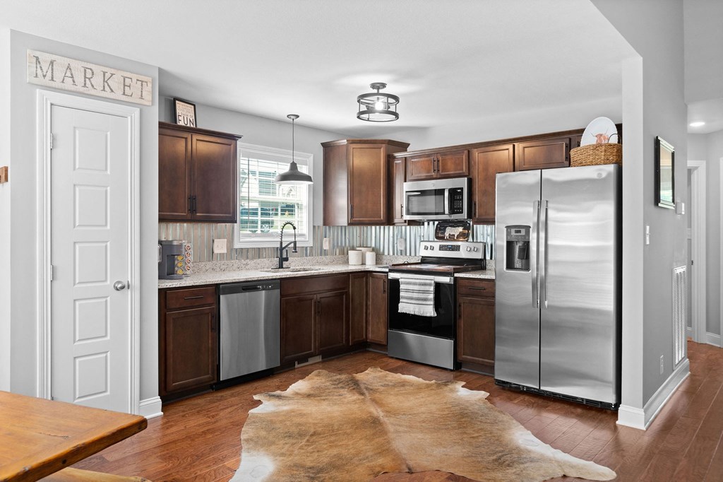 a kitchen with stainless steel appliances and a rug on the floor