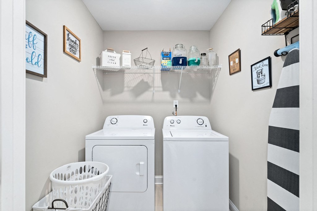 a white laundry room with two washes and a dryer