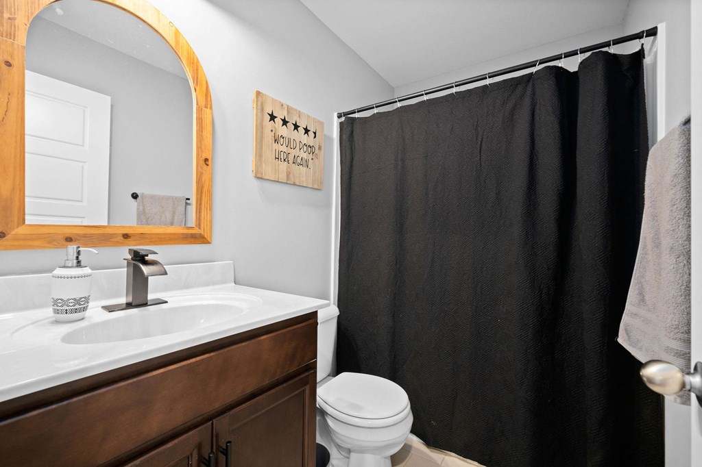 a bathroom with a black shower curtain and a white toilet