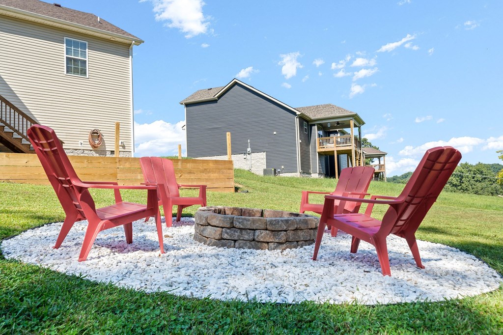 two red chairs sitting around a fire pit in the yard