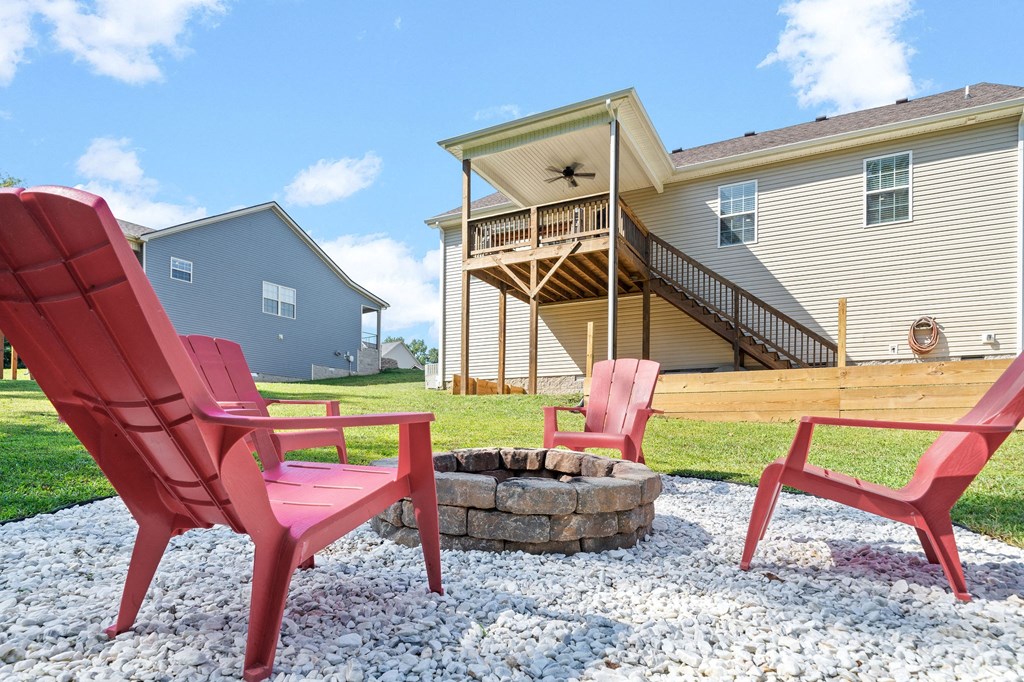 two red chairs sitting around a fire pit in front of a house