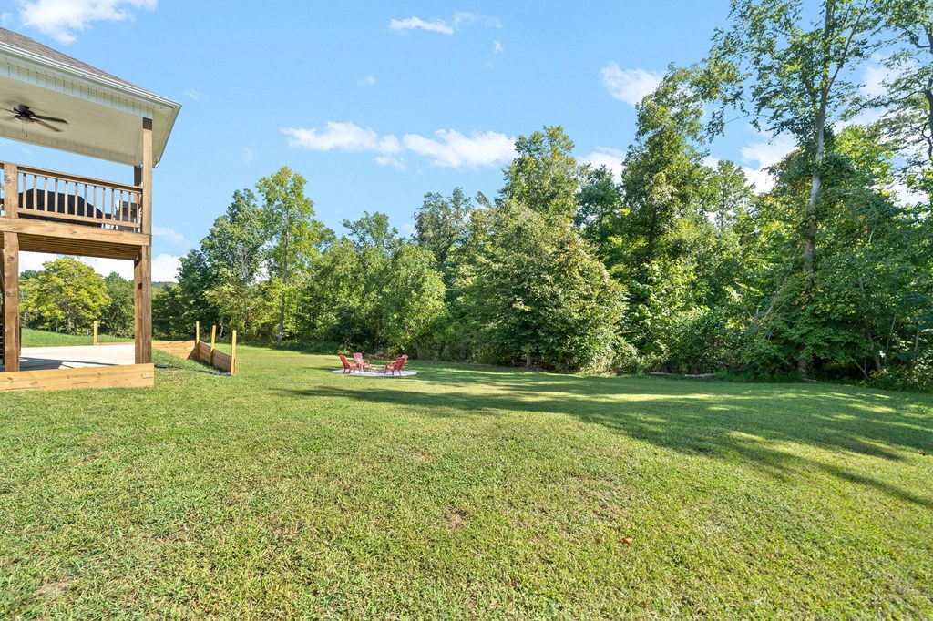a backyard with grass and trees and a deck with a picnic table