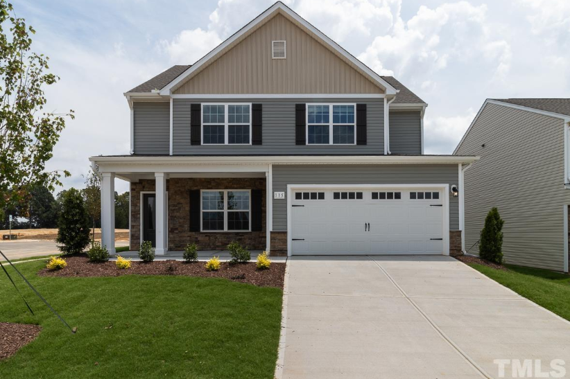 a house with a garage door in front of a lawn