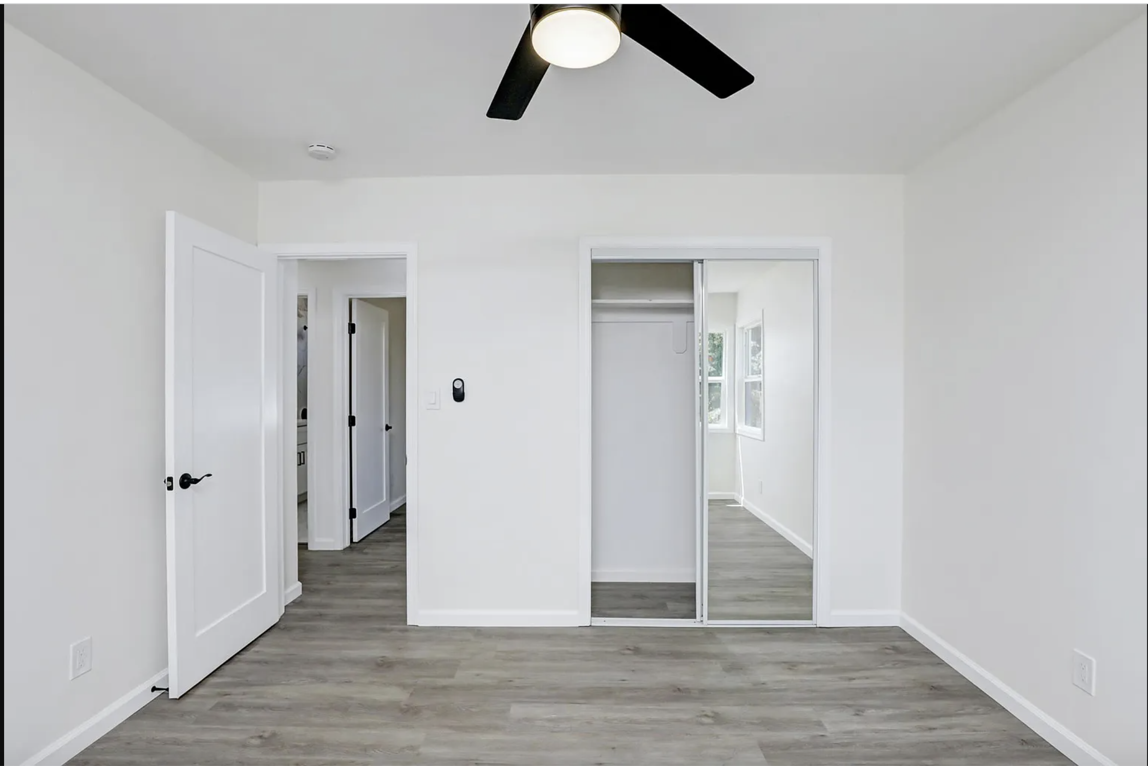 a living room with white walls and a ceiling fan