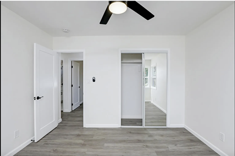 a living room with white walls and a ceiling fan