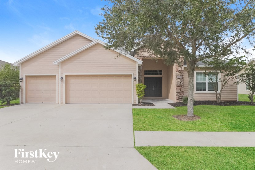 A house with a garage and a tree in front of it.