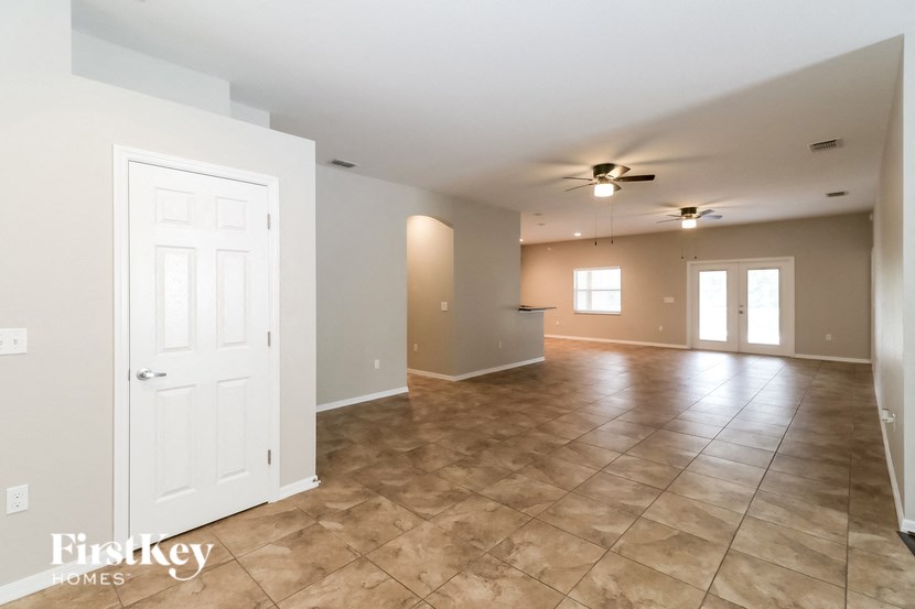A spacious room with tile flooring and a ceiling fan.