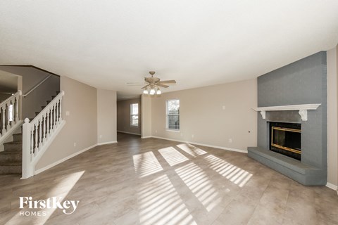 A spacious living room with a fireplace and a staircase.