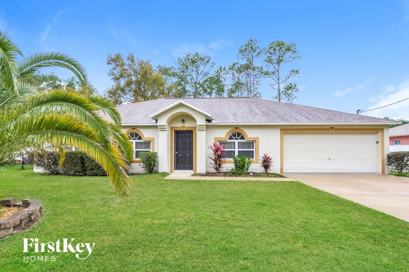 A house with a well-maintained lawn and a palm tree in front.