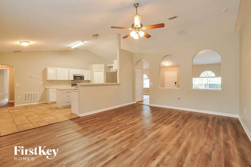 A spacious living room with wooden floors and a ceiling fan.
